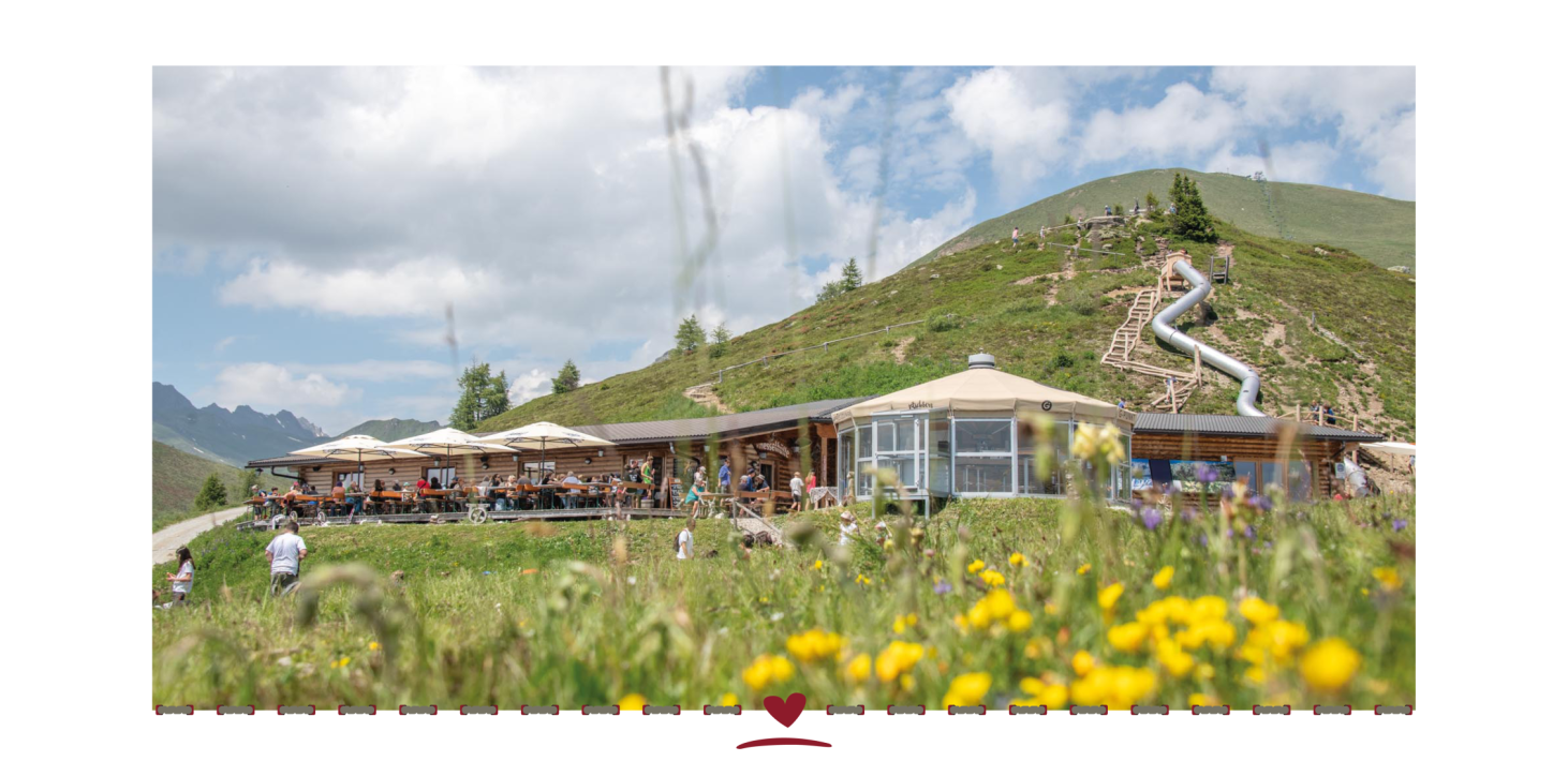 Due cabinovie sopra la pista da sci. Sullo sfondo, un ristorante di montagna e un paesaggio innevato sotto un cielo azzurro.