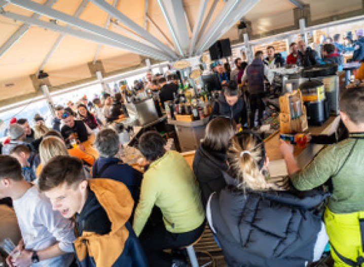 Many people gathered around tables in an après-ski bar, celebrating.