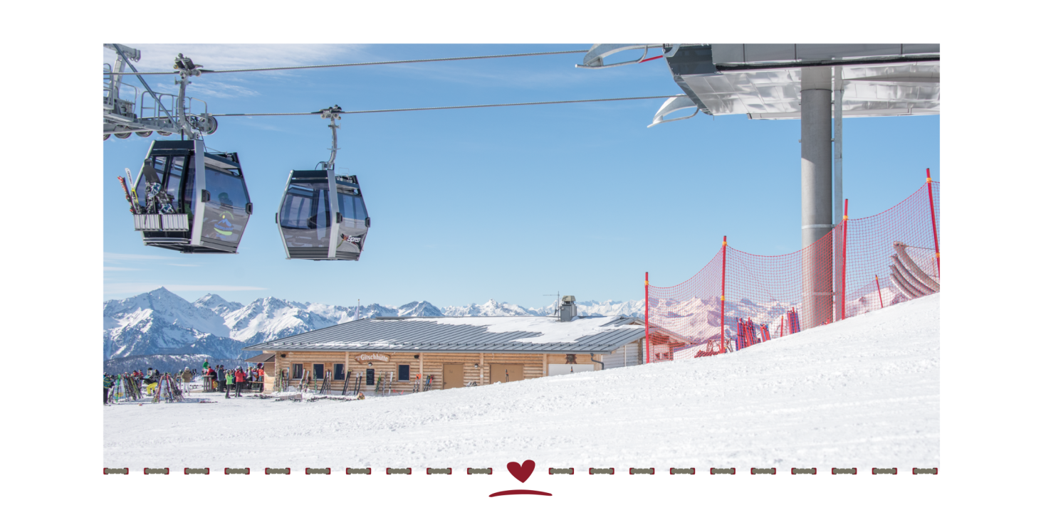 Two cable cars above the ski slope. In the background, a mountain restaurant and a snow-covered landscape under a blue sky.